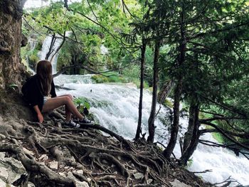 Woman sitting by waterfall at national park