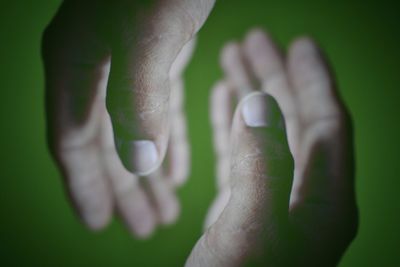 Close-up of hand against green leaf