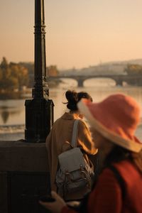 Rear view of man and woman sitting against sky at sunset