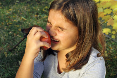 Girl holding fruit while sitting on field