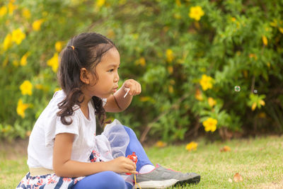 Girl looking away while sitting outdoors