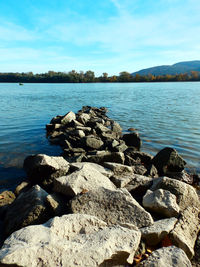 Rocks by lake against sky