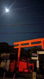 Low angle view of illuminated sign against sky at night