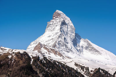 Low angle view of snowcapped mountain against blue sky