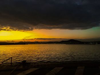 Scenic view of sea against dramatic sky during sunset