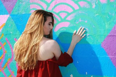 Rear view of woman touching colorful graffiti wall