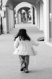 Rear view of girl running on footpath