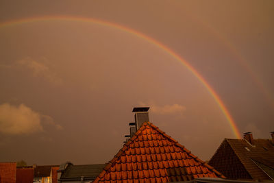 Low angle view of rainbow over building against sky