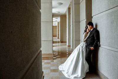 Wedding couple standing in corridor against wall