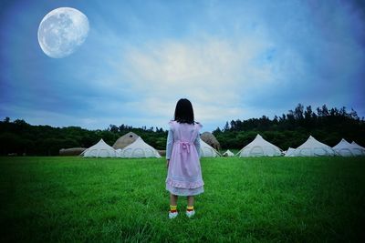 Rear view of woman standing on field against sky