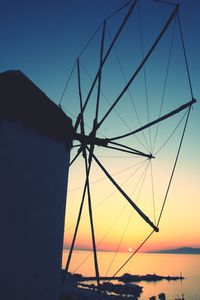 Low angle view of silhouette cranes against clear sky during sunset