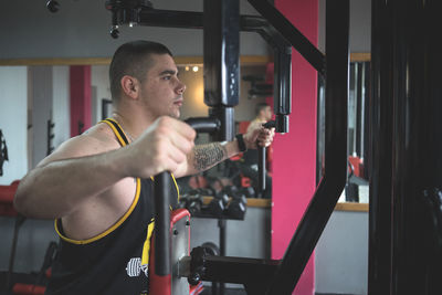 Side view of young man exercising in gym