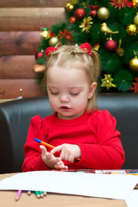 A little girl draws on the background of the christmas tree. the concept of waiting for the holiday.