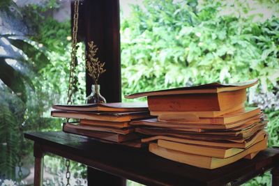 Stack of books on table against trees