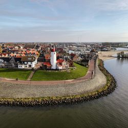 Aerial view of townscape by river against sky