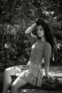 Portrait of woman sitting on tree trunk