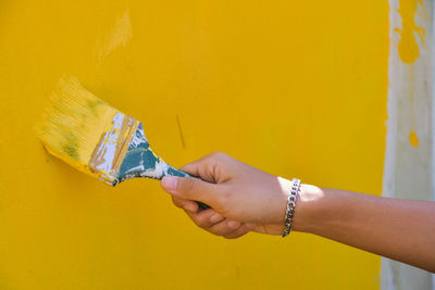 Close-up of woman hand holding yellow wall