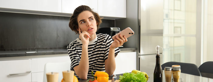 Portrait of young woman using mobile phone at home