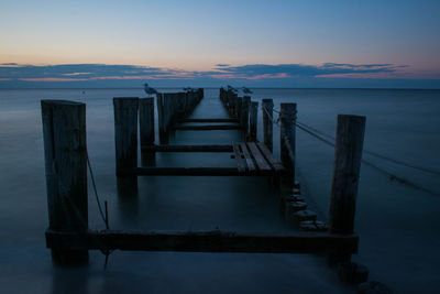 Pier over sea against sky during sunset