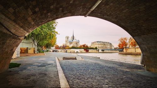 Arch bridge over river amidst buildings in city