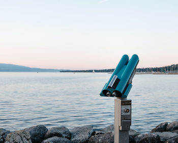 Coin-operated binoculars by sea against clear sky