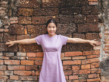 Portrait of smiling woman standing against brick wall