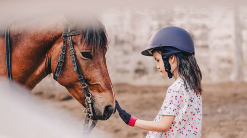 Side view of girl with horse outdoors