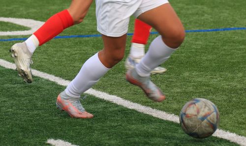 Low section of man playing soccer on field