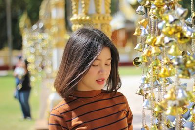 Close-up of woman with eyes closed standing by christmas decorations during sunny day