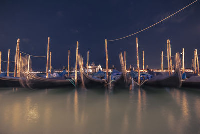Boats moored in sea against sky at night