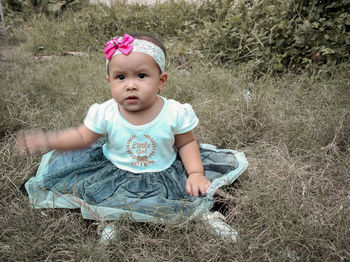 Portrait of cute girl sitting on field