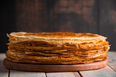 Traditional russian food - thin pancakes. a stack of crepes on a dark brown wooden background. 