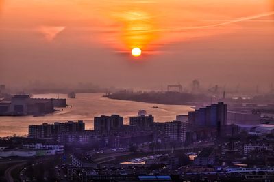 High angle view of cityscape by river during sunrise