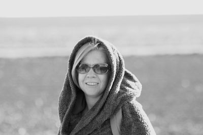 Portrait of smiling mature woman wearing sunglasses standing at beach