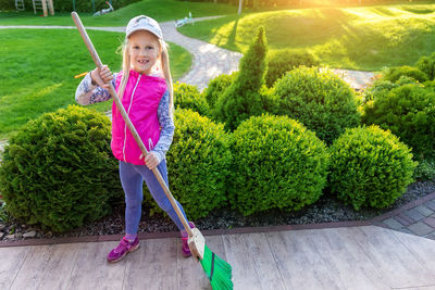 Full length portrait of smiling girl swiping footpath