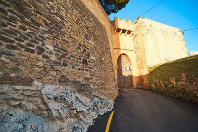 Stone wall of old building against sky