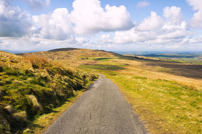 Road leading towards landscape against sky