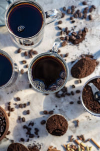 Still life with glass mugs of black hot coffee, coffee beans, ground coffee, making coffee at home