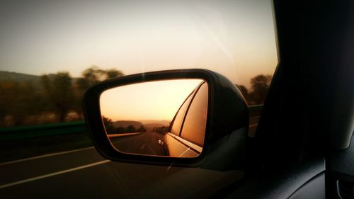 Close-up of side-view mirror against sky