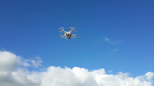 Low angle view of helicopter flying against blue sky