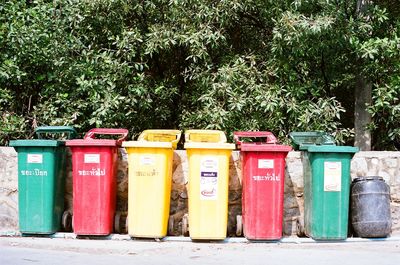 Multi colored garbage bin against trees