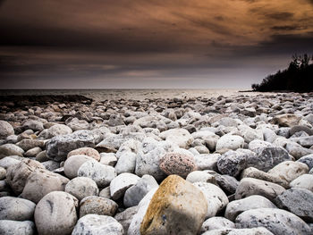 Pebbles on beach against sky during sunset