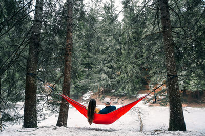 People on snow covered land against trees in forest