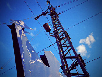 Low angle view of electricity pylon against blue sky