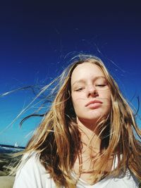 Close-up of young woman against clear blue sky