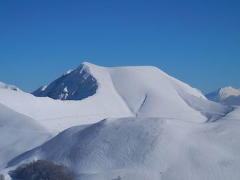 Scenic view of snowcapped mountains against clear blue sky