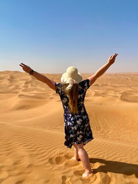 Rear view of woman standing at sandy beach