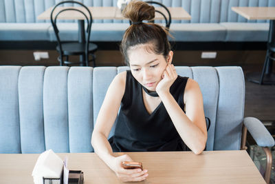 Woman using mobile phone while sitting in restaurant