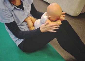 Midsection of father holding baby sitting at home