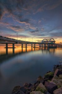 Bridge over river against sky during sunset